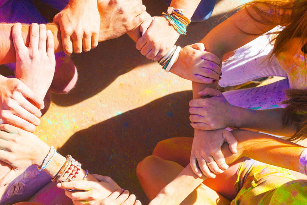 Friends putting their hands together in a sign of unity and teamwork. Holi colors festival. Friendship concept